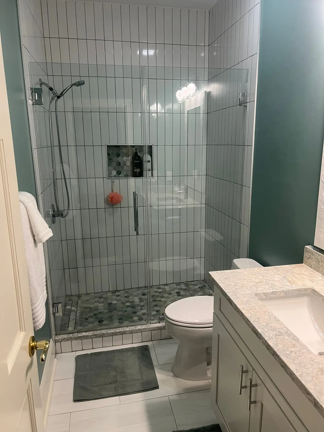 A finished guest bathroom with a tiled walk-in shower and a quartz vanity