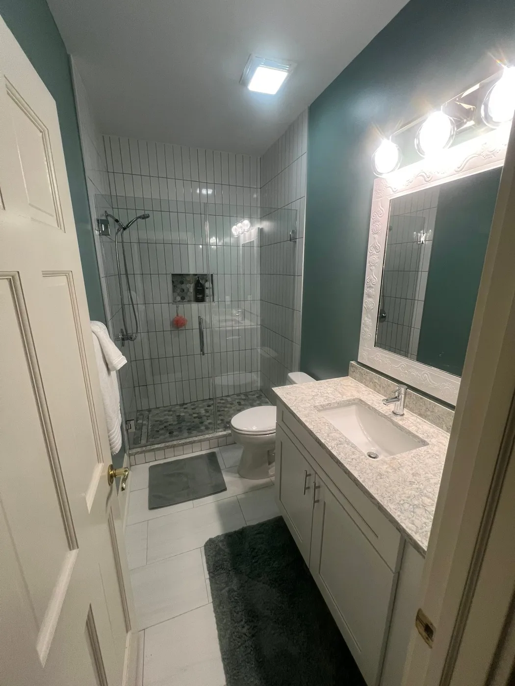 A finished guest bathroom with a quartz vanity and a tiled walk-in shower
