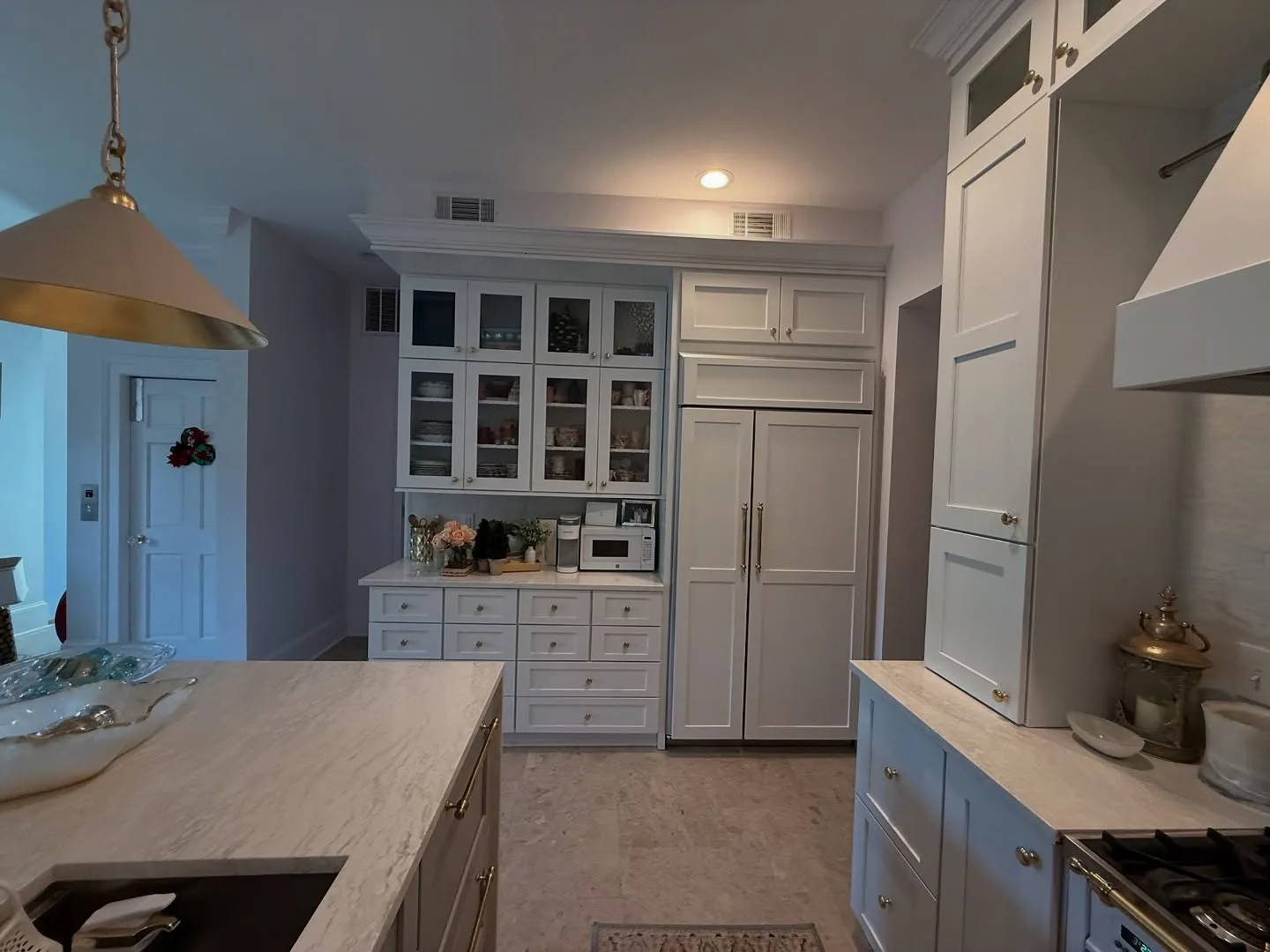 Glass-front upper cabinets with brass hardware above a white kitchen