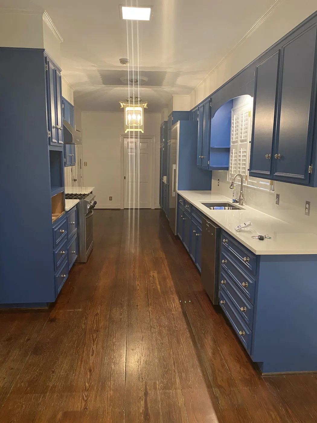 Blue galley kitchen cabinets running the length of a long room