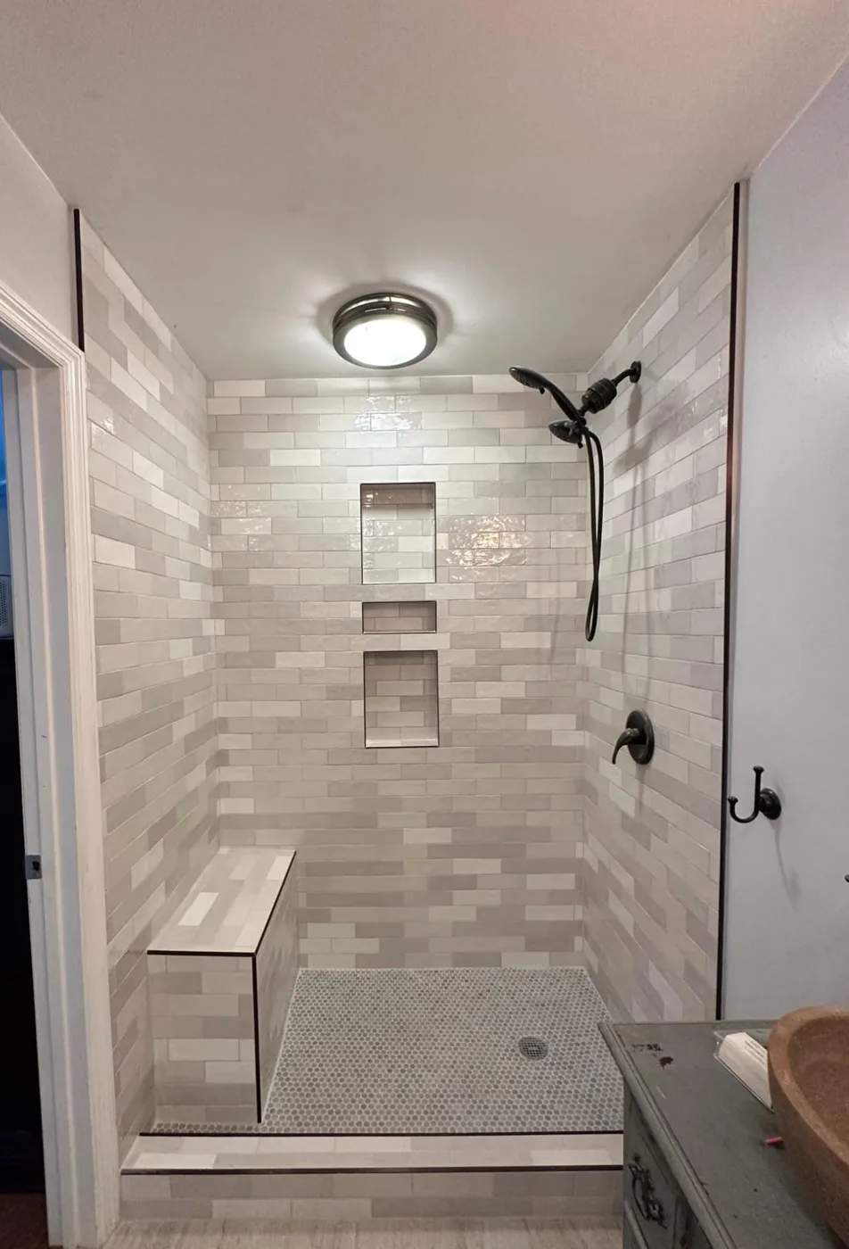 The finished tiled shower with a bench and two niches