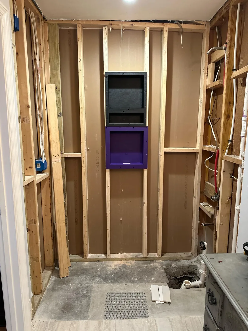 A shower halfway through the remodel, with the old tile removed and new built-in shelves in the wall