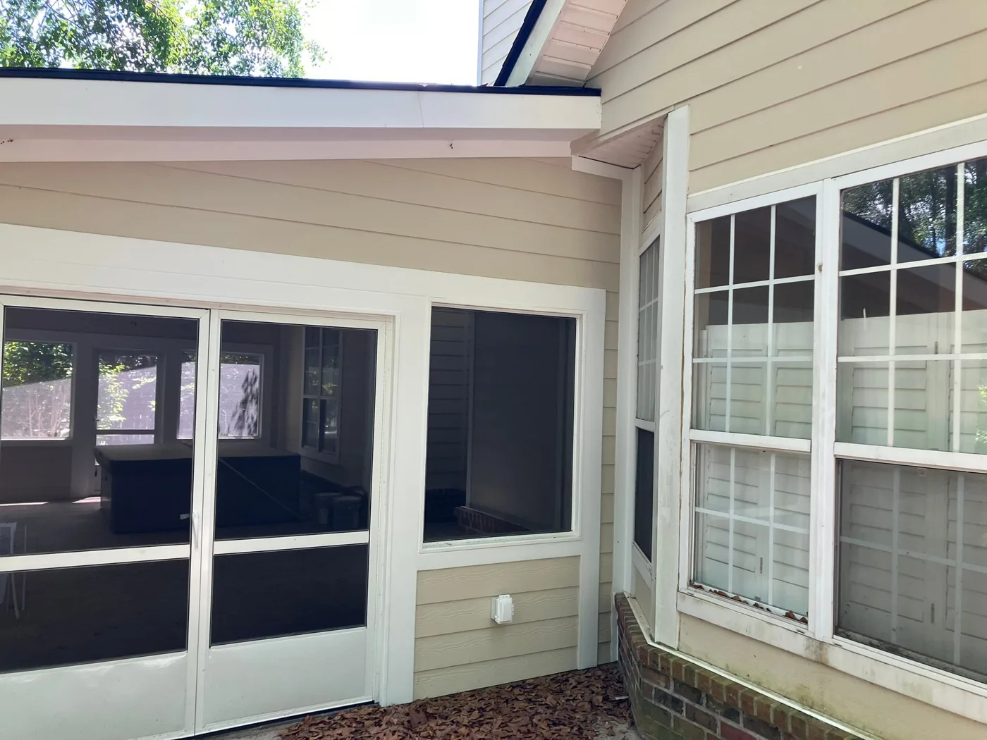 The outside of a new sunroom addition with French doors and wide windows